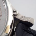 007 シルバーの腕時計のクローズアップショット、ベルト部分と時計面の詳細な画像。.