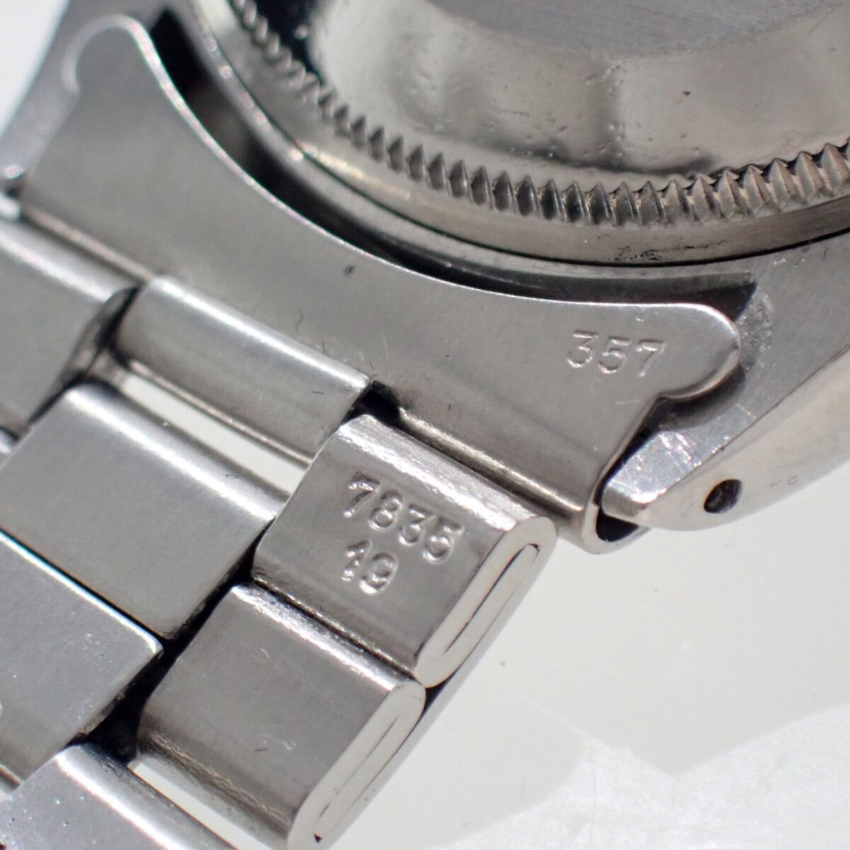Stainless steel watch close-up with engraved numbers and serial details.