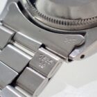 Stainless steel watch close-up with engraved numbers and serial details.