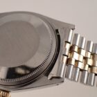 シルバーのメタル腕時計のクローズアップ画像。ゴールドとシルバーのリンクバンドが特徴的です。.